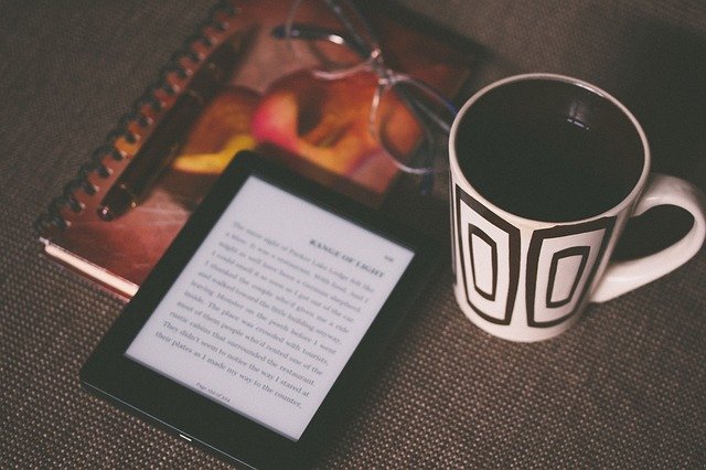 Kindle e-reader, coffee and notepad